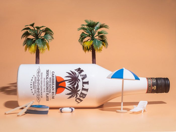 A lifestyle product photography shot of a malibu bottle against an orange background