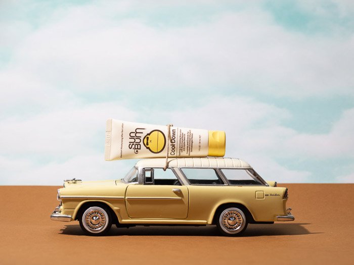 Lifestyle product photography shot featuring a sunscreen bottle on the roof of a miniture car
